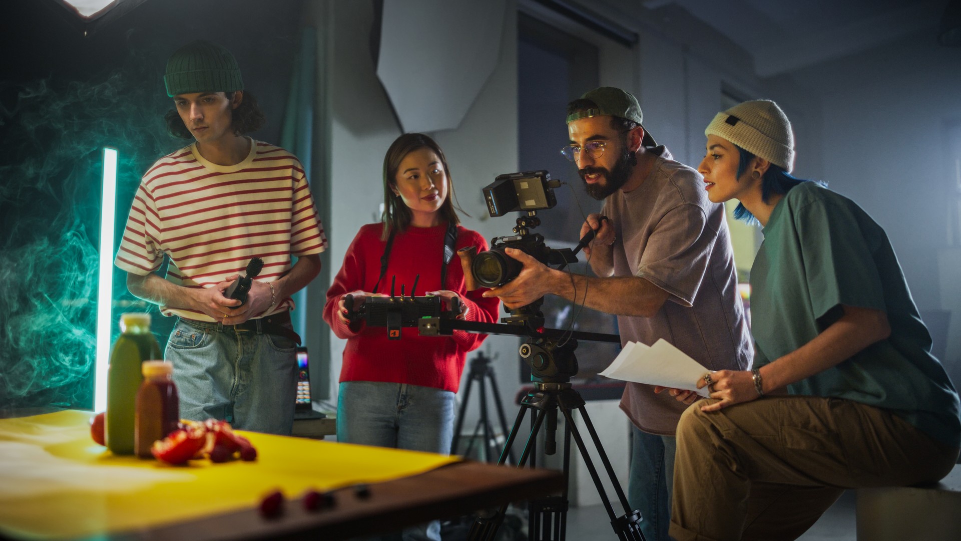 Un equipo de filmación joven y diverso participó en una sesión de producción de video creativo en un set vibrante, rodeado de equipos modernos y accesorios coloridos, centrándose en capturar contenido atractivo para un proyecto dinámico